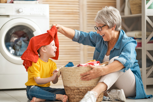 grandma and grandson playing with fresh laundry smiling