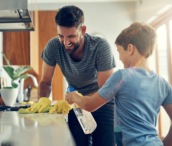 father and son having fun and smiling cleaning kitchen