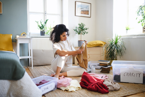 woman deciding how to organise and declutter items into charity and keep boxes