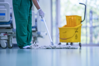 medical facility cleaner sweeping floors in hospital corridor